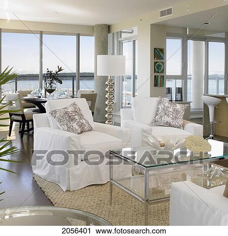 Stock Image - Living Room With White Furniture And Sea View In Background. Fotosearch