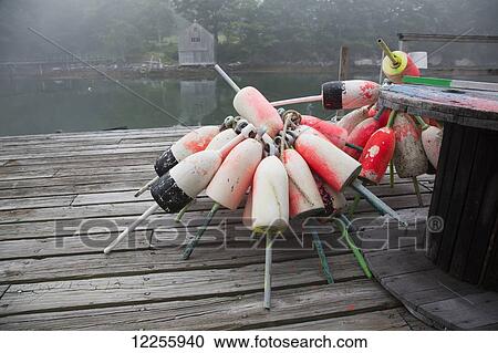 Stock Image - Lobster trap buoys and paint wheel on wooden dock; New Harbor, Maine, United States of America. Fotosearch