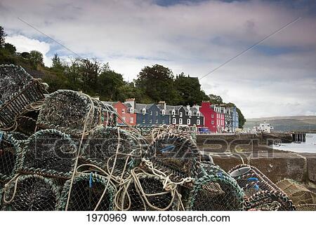 Stock Photo - Lobster Traps On The Shore With A Row Of Colourful Houses At The Water's Edge In The Background; Tobermory Isle Of Mull Scotland. Fotosearch