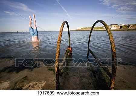 Stock Photo - Local Kids Dive From The Wall. Fotosearch