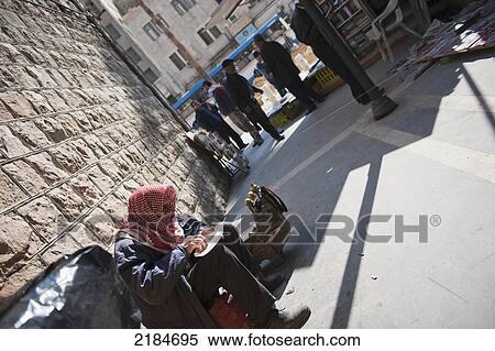 Stock Photography - Local Man Tucks Into A Slice Of Kunafeh Outside Habibah Arabic Sweet Shop, Amman, Jordan, Middle East. Fotosearch
