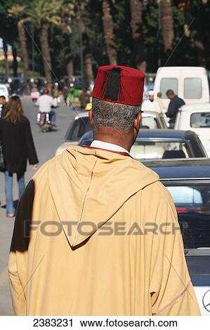 Stock Image - Local man wearing long-hooded cloak known as a djellaba, near Djamaa El Fna, the main square in Marrakesh; Morocco. Fotosearch