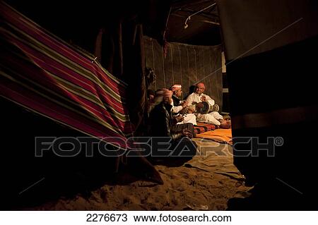 Stock Image - Local musicians entertain tourists in a Bedouin tent run by Captain's Camp who offer overnight camping accommodation in the desert; Wadi Rum, Jordan. Fotosearch