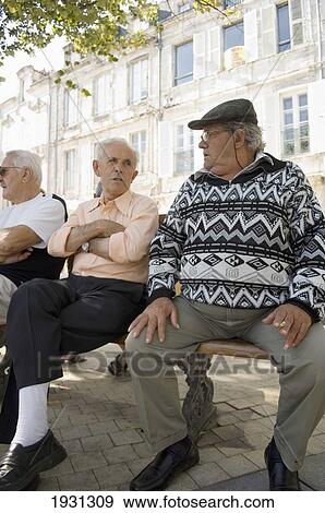 Stock Photo - Local residents enjoy the shaded street benches in the fortified town of La Rochelle, La Rochelle, Poitou-Charentes region of France.. Fotosearch