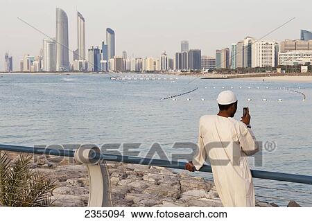 Picture - Local UAE man looking at Abu Dhabi cityscape; Abu Dhabi, United Arab Emirates. Fotosearch