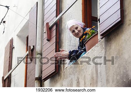 Stock Photograph - Local woman looks from her window in Old Town Rovinj, Istria, Croatia.. Fotosearch