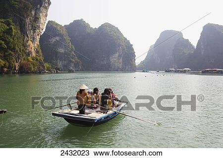 Stock Image - Local woman rowing boat with tourists to the Vung Vieng Fishing Village in Bai Tu Long Bay, Halong Bay; Vietnam. Fotosearch