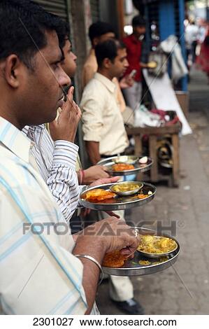 Stock Photo - Locals eat plate-meal while standing up at this cheap on-street cafe in centre of Calcutta / Kolkata, the capital of West Bengal State, India, Asia.. Fotosearch