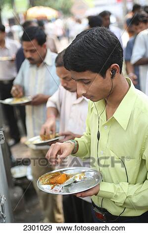 Stock Photo - Locals eat plate-meal while standing up at this cheap on-street cafe in centre of Calcutta / Kolkata, the capital of West Bengal State, India, Asia.. Fotosearch