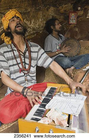 Stock Image - Locals singing mantras (kirtan) accompanied by harmonium; Pashupathinath, Nepal. Fotosearch