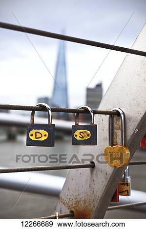 Stock Photo - Locks placed on the railings of the Millenium Bridge with The Shard in the background; London, England. Fotosearch