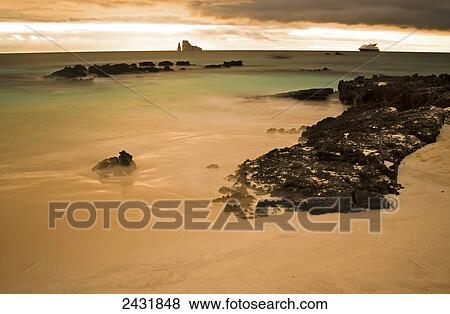 Stock Photo - Long exposure of beach in the Galapagos Islands with cruise ship in the distance; San Cristobal Island, Galapagos, Ecuador. Fotosearch