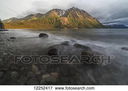 Long exposure of Kathleen Lake washing over the rocks as the setting sun hits King's Throne, Kluane National Park; Yukon, Canada View Large Photo Image Stock Photo - Long exposure of Kathleen Lake washing over the rocks as the setting sun hits King's Throne, Kluane National Park; Yukon, Canada. Fotosearch