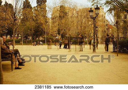 Stock Photography - Long exposure of people strolling around a park with a sepia tint near La Sagrada Familia; Barcelona, Spain. Fotosearch