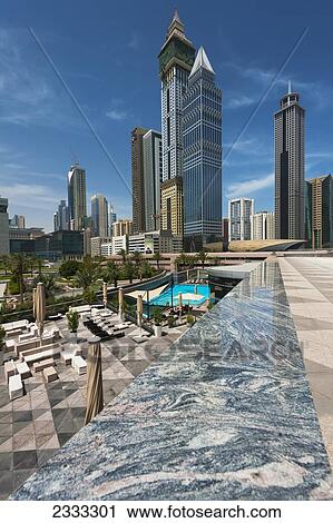 Stock Image - Looking Across Hotel Swimming Pool To Difc (Dubai International Financial Centre); Dubai, United Arab Emirates. Fotosearch