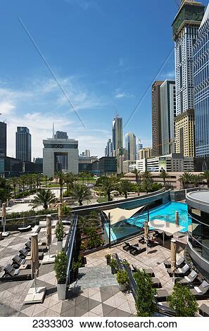Stock Image - Looking Across Hotel Swimming Pool To Difc (Dubai International Financial Centre); Dubai, United Arab Emirates. Fotosearch