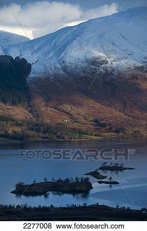 Stock Photo - Looking across Loch Leven with patch of sun on remote house; Highlands, Scotland. Fotosearch