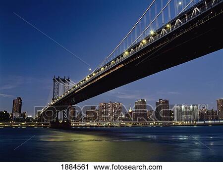Stock Image - Looking Along Manhattan Bridge At Dusk Over The East River To The Lower East Side And The Empire State Building Behind. Fotosearch