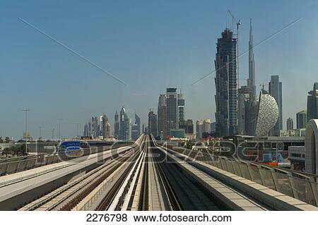Stock Photo - Looking along train track to the Burj Khalifa and other buildings; Dubai, United Arab Emirates. Fotosearch