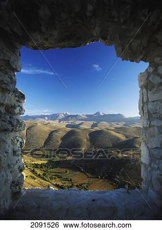 Stock Photograph - Looking Out From Old Window In Ruins Of Buildings Beside Rocca Calascio To The Campo Imperatore And Parco Nazionale Gran Sasso At Dawn, Abruzzo, Italy.. Fotosearch