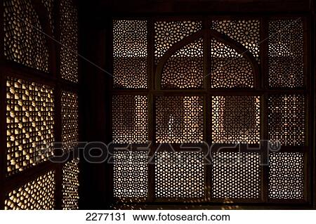 Stock Image - Looking through stone lattice wall to man praying in the Jami Masjid; Fatehpur Sikri, Agra, India. Fotosearch