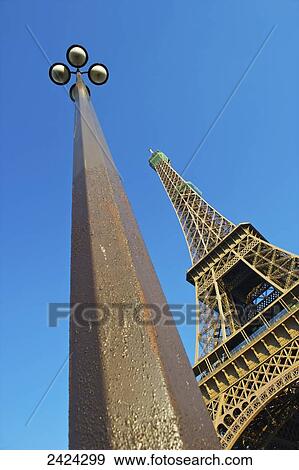 Stock Photo - Low angle view of a lamp post and the Eiffel Tower against a blue sky; Paris, France. Fotosearch