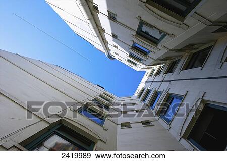 Stock Photo - Low angle view of a white building with windows and walls on five sides and a blue sky; Hamburg, Germany. Fotosearch
