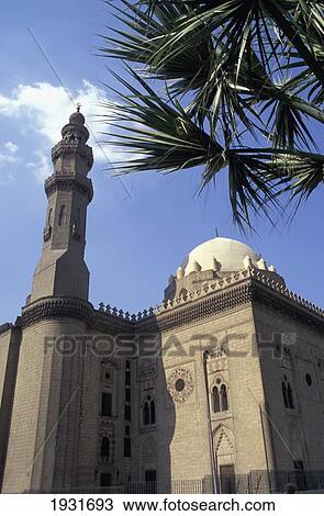 Stock Image - Low Angle View Of Minaret And Dome Of Sultan Hassan Mosque With Palm Tree, Cairo, Egypt; Cairo, Egypt. Fotosearch
