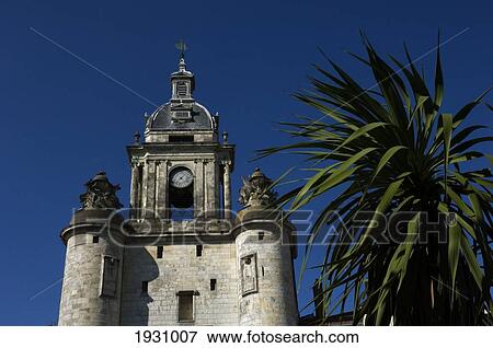 Low Angle View Of Porte De La Grosse Horloge, An Old City Gate, And A Palm Tree, La Rochelle; Poitou-Charentes, France View Large Photo Image Stock Photo - Low Angle View Of Porte De La Grosse Horloge, An Old City Gate, And A Palm Tree, La Rochelle; Poitou-Charentes, France. Fotosearch