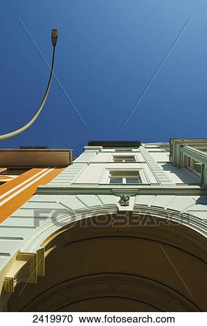 Stock Image - Low angle view of the facade of a building with an archway and street light against a blue sky; Hamburg, Germany. Fotosearch