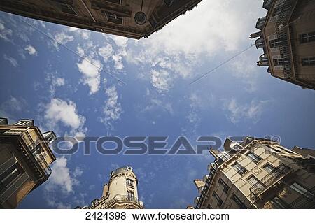 Stock Photo - Low angle view of the tops of various buildings against a blue sky with cloud; Paris, France. Fotosearch