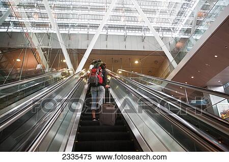 Stock Photography - Low Angle View Of Woman On Escalator; Singapore. Fotosearch