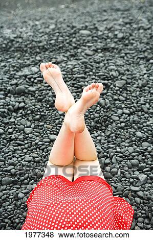 Stock Photo - low section, Woman lying on black rocks. Fotosearch