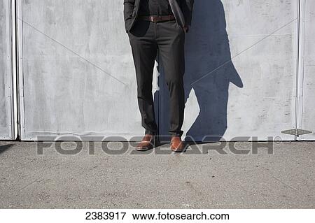 Stock Photo - Lower half of man in suit in front of airplane hangar; Langley, British Columbia, Canada. Fotosearch