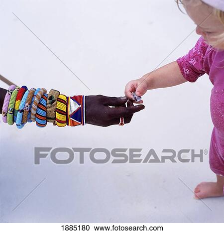 Stock Image - Maasai Passing A Young Child A Shell, Close Up. Fotosearch