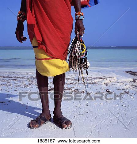 Stock Photo - Maasai Vendor Holding Jewelry On The Beach, Low Angle View. Fotosearch
