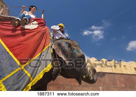 Stock Image - Mahout And Tourist On Elephant At Amber Fort, Side View. Fotosearch