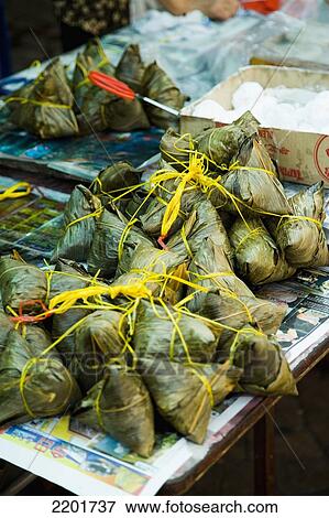 Malaysia, on market stall table at Jalan Petaling (Petaling Street) in Chinatown; Kuala Lumpur, wrapped in banana leaves, coconut rice parcels, Nasi Lemak View Large Photo Image Stock Photo - Malaysia, on market stall table at Jalan Petaling (Petaling Street) in Chinatown; Kuala Lumpur, wrapped in banana leaves, coconut rice parcels, Nasi Lemak. Fotosearch