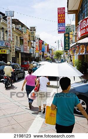 Stock Image - Malaysia, Pulau Pinang (Penang), banners and neons in street advertising local businesses; Georgetown, People walking down busy street. Fotosearch