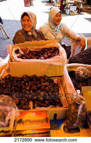 Stock Image - Malaysia, Terengganu, Pasar Payang central market; Kuala Terengganu, Female stall keepers selling dates at large indoor and outdoor market. Fotosearch