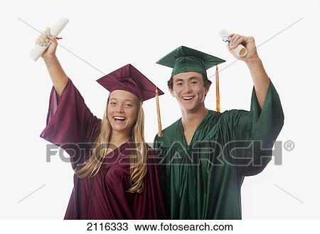 Stock Image - Male and female graduates in cap and gown, holding diplomas.. Fotosearch