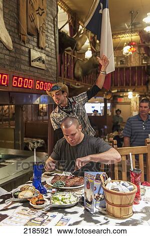 Stock Image - Male Contestant Begins An Attempt At The 72 Oz Steak Challenge, The Big Texan Steak Ranch Restaurant, Amarillo, Texas, Usa. Fotosearch