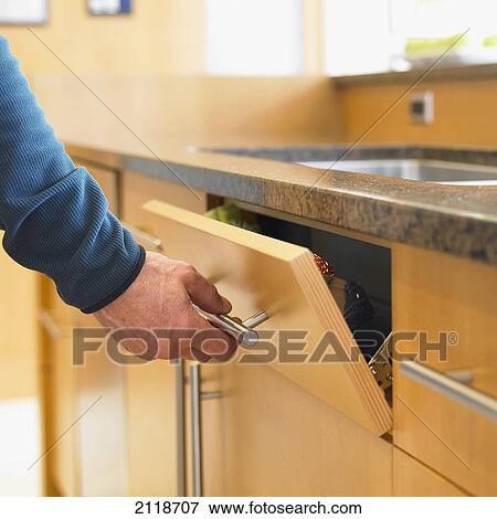 Stock Photo - Male Hand Opening Modern Kitchen Drawer; Victoria Vancouver Island British Columbia Canada. Fotosearch