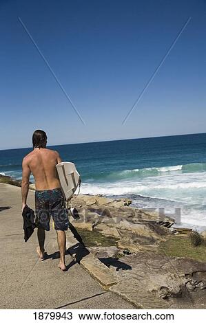 Stock Image - Male Surfer Walking Between Bondi Beach And Bronte Beach. Fotosearch