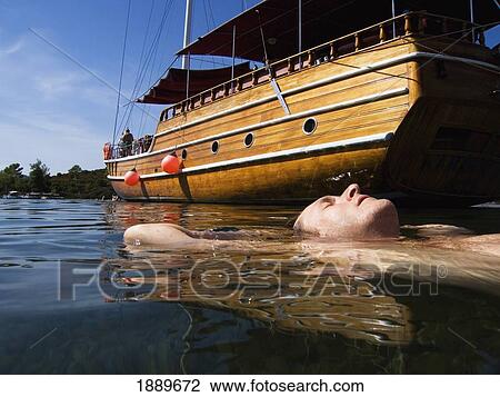 Male Swimmer Floating Alongside A Moored Boat View Large Photo Image Stock Image - Male Swimmer Floating Alongside A Moored Boat. Fotosearch