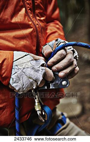 Stock Photograph - Man adjusting rock climbing equipment in the Adirondacks; New York, USA. Fotosearch