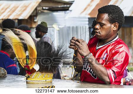 Stock Photo - Man and headdress of bird of paradise or cassowary feathers for sale at the market, Wamena, Papua, Indonesia. Fotosearch