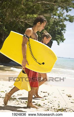 Stock Photograph - Man And Woman Going Bodyboarding. Fotosearch