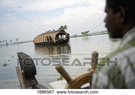 Stock Photo - Man At Steering Wheel Of House Boat. Fotosearch