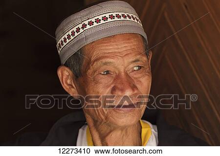 Stock Image - Man attending a funeral ceremony at a rante, the ceremonial site for a Torajan funeral, in Sereale, Toraja Land, South Sulawesi, Indonesia. Fotosearch